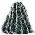 Decorative tinsel tree with a hand holding it on a white background