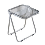 Chrome folding stool on a carpeted floor with a plant in the background